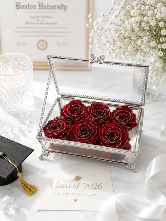 Silver box with red roses, graduation cap, and diploma on a white surface