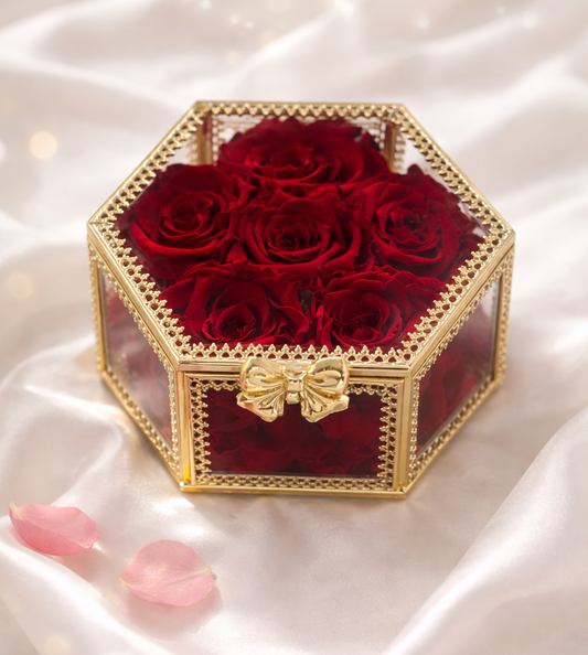 Hexagonal gold box with red roses on a white satin background